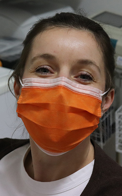 A dental nurse wearing an orange face mask