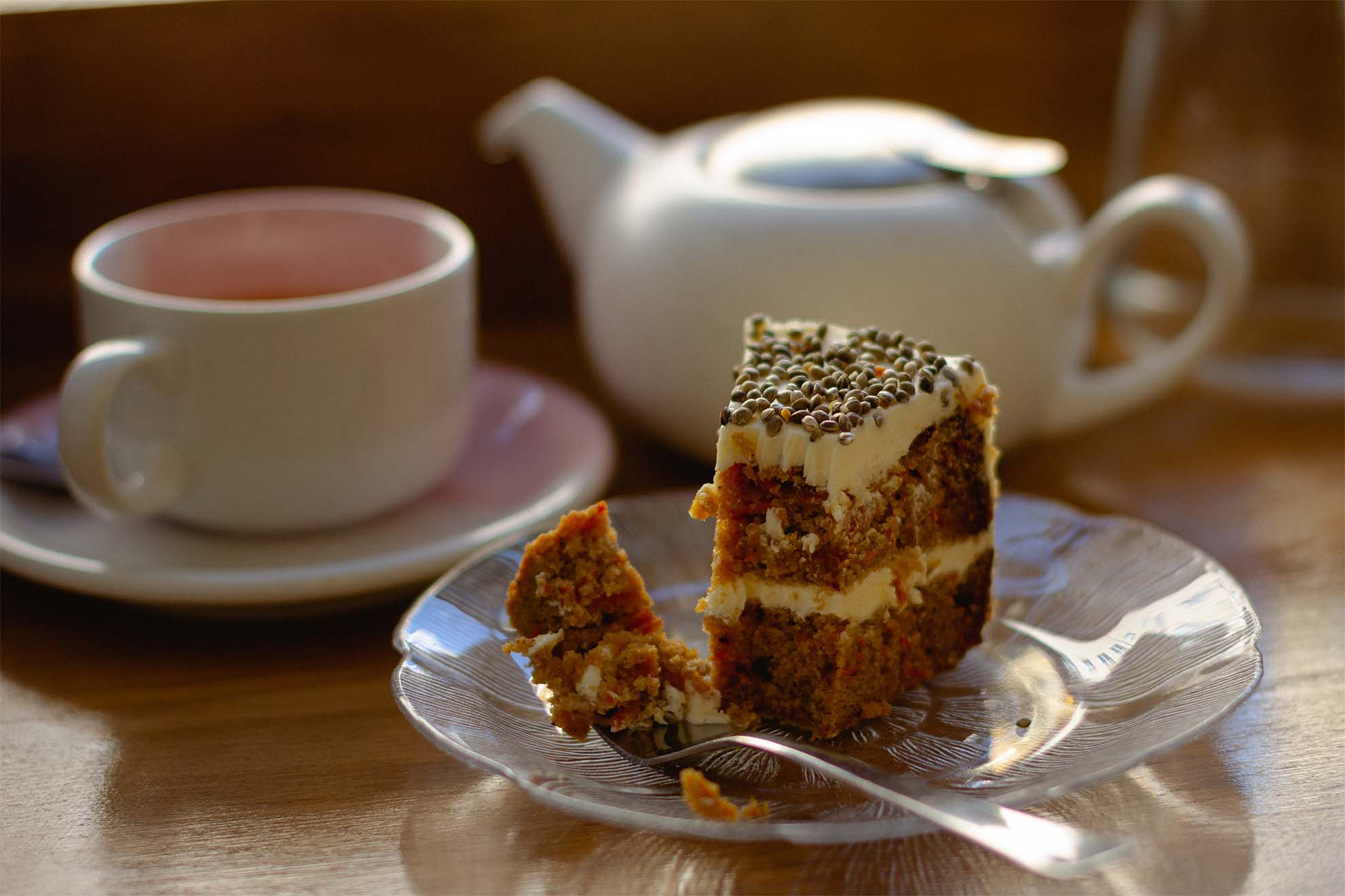 A piece of cake on a plate with a cup of tea