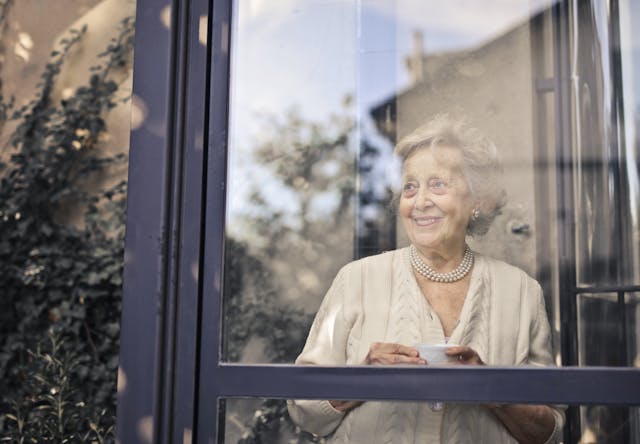 older lady with grey hair looking through window