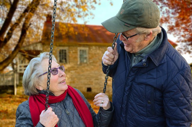 older lady on a swing and older man talking to her