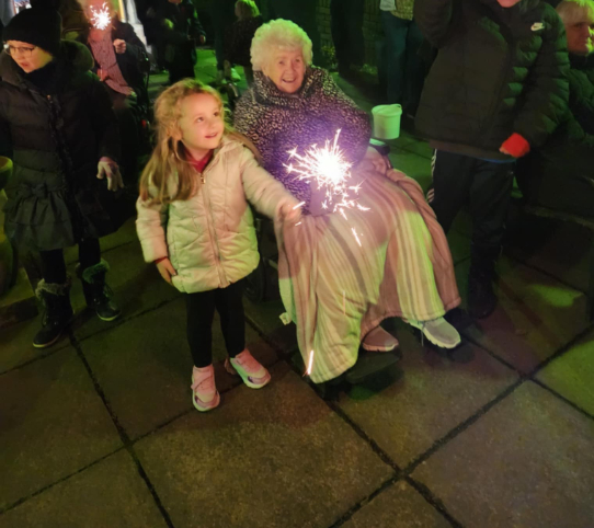 Residents and guests at Beechgrove Care Home enjoying a colourful fireworks display in the garden, surrounded by family, friends, and cosy cups of hot chocolate.