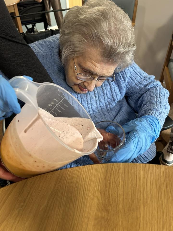 older lady sat down pouring a smoothie