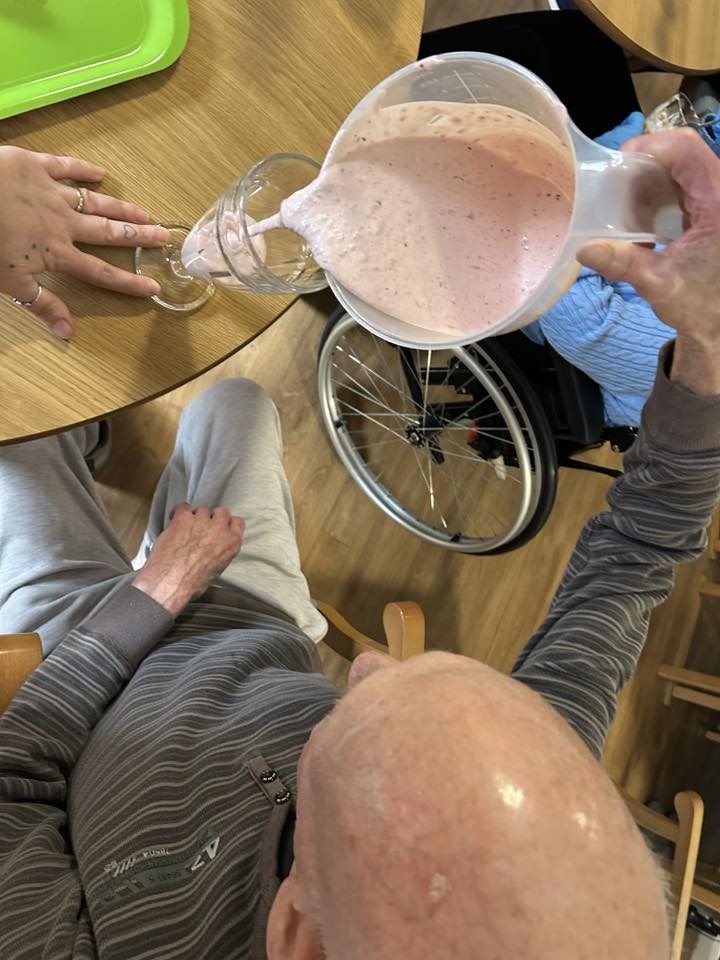 older man sat down pouring a smoothie