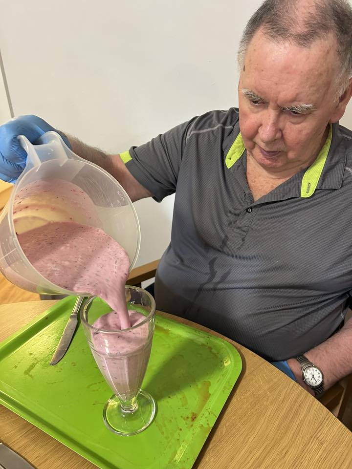 older man sat down pouring a smoothie