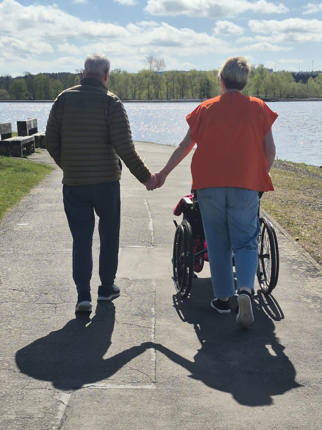 resident and carer holding hands on an outdoor walk