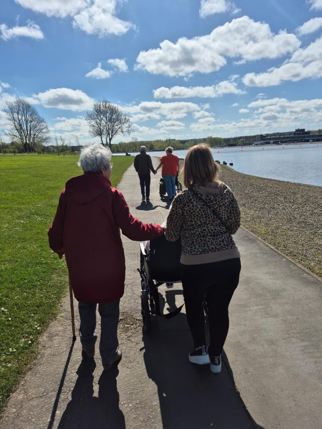care home residents and staff on a sunny park walk
