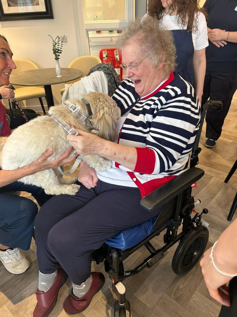 female resident smiling wide with a small dog on her lap
