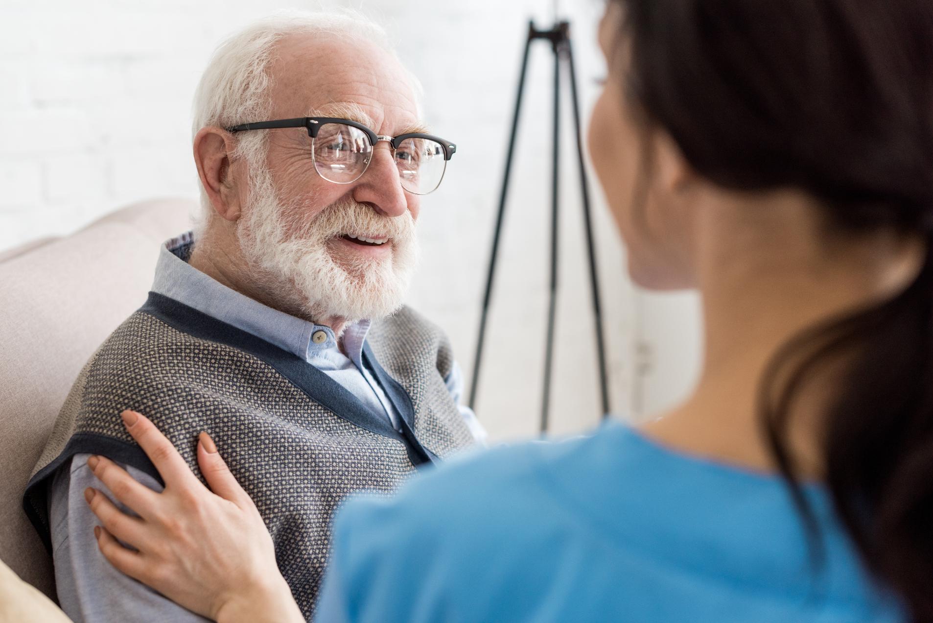 nurse comforting a smiling elderly man